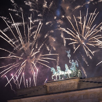 Feuerwerk zum Jahreswechsel steigt während der Feier „Silvester am Brandenburger Tor“ hinter dem Brandenburger Tor auf.