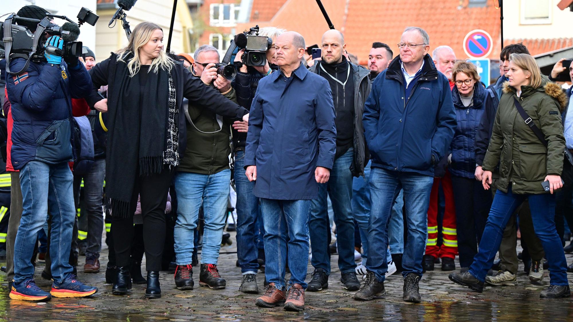 Bundeskanzler Olaf Scholz und Stephan Weil, Ministerpräsident von Niedersachsen, stehen bei ihrem Besuch im Hochwassergebiet an einer überfluteten Straße.