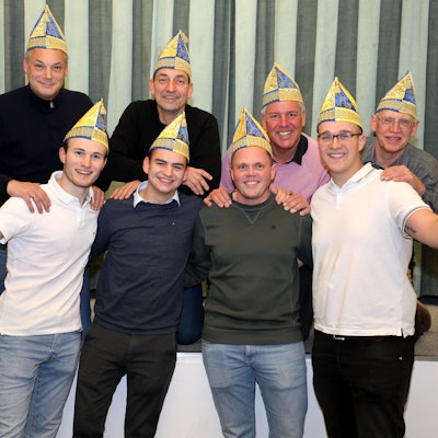 In zwei Reihen hintereinander aufgestellt stehen die Mitglieder des Vorstands mit Narrenkappen auf dem Kopf.