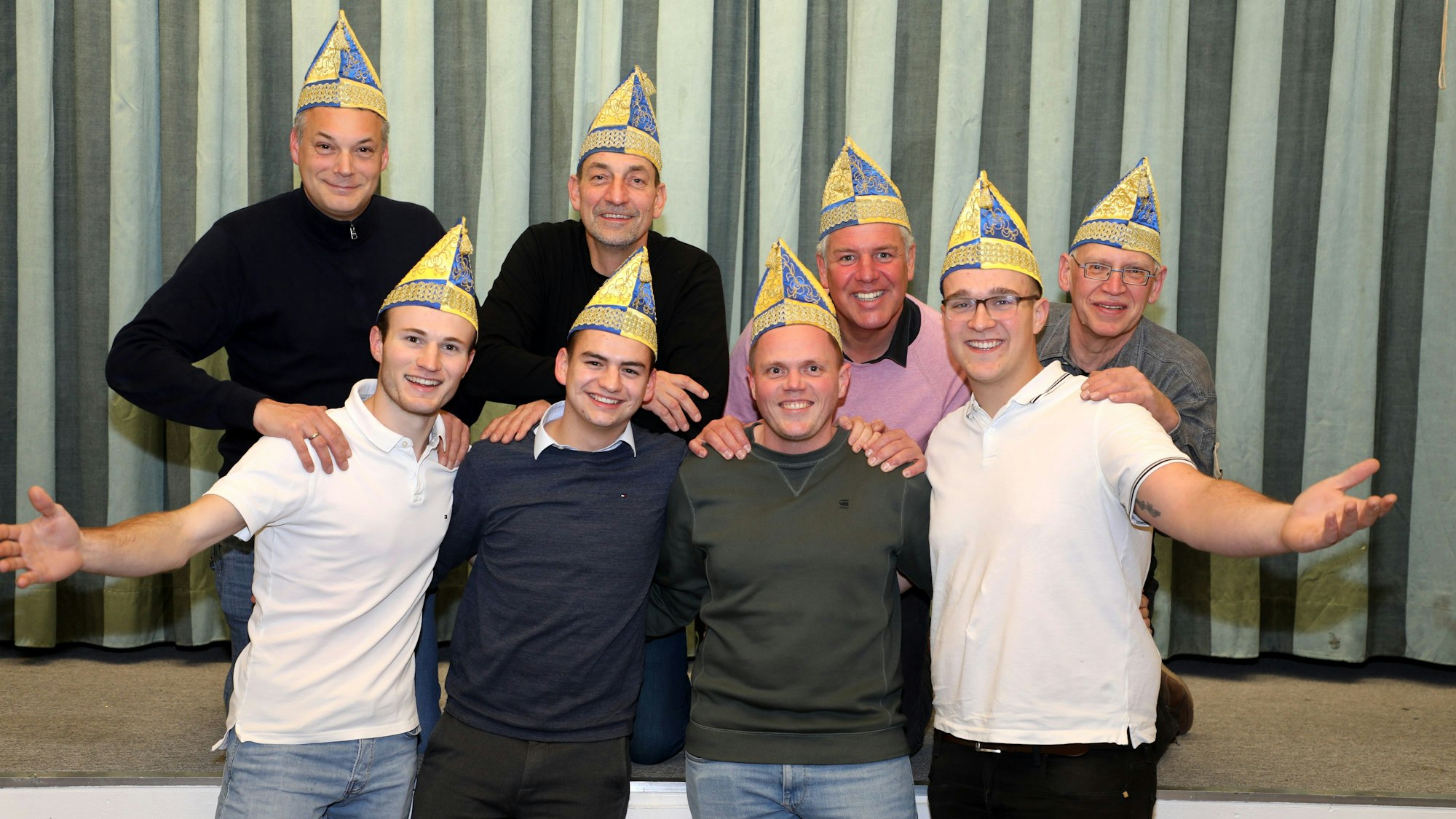 In zwei Reihen hintereinander aufgestellt stehen die Mitglieder des Vorstands mit Narrenkappen auf dem Kopf.