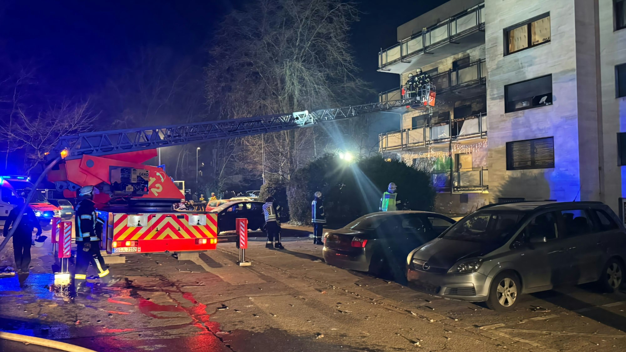 Über eine Drehleiter gelangen Feuerwehrleute auf einen Balkon eines mehrstöckigen Hauses.