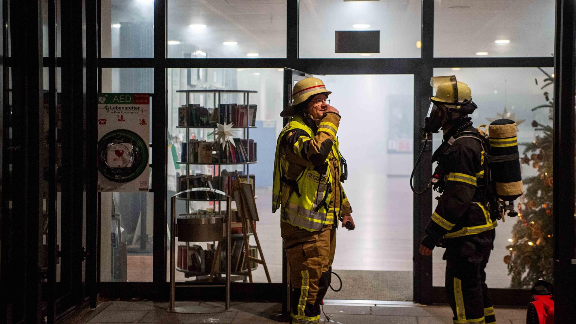 Zwei Feuerwehrleute, einer mit Atemschutzausrüstung, vor dem verrauchten Foyer der Kreisverwaltung in Euskirchen.