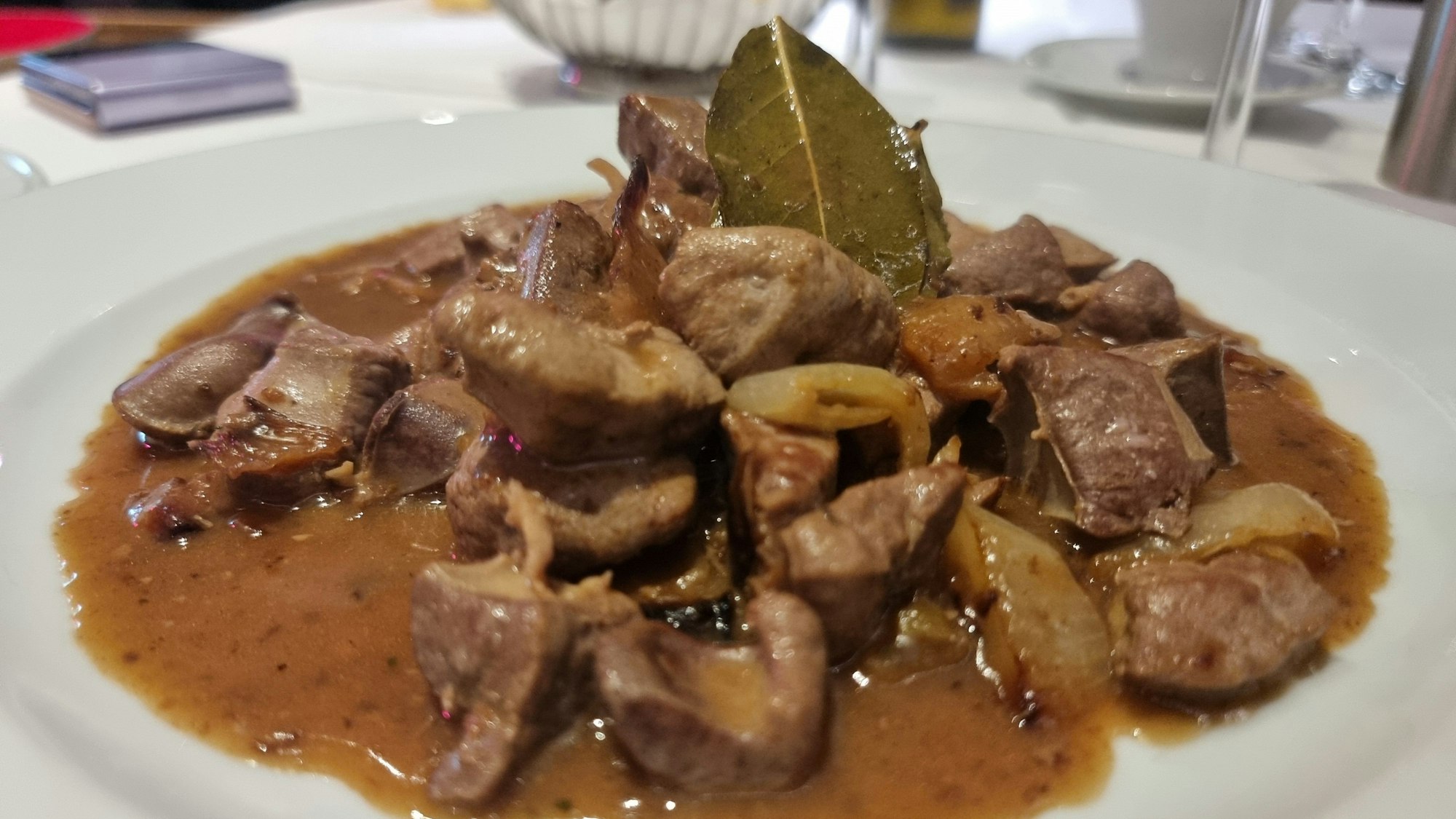 Fleischstücke liegen auf einem Teller in Soße.