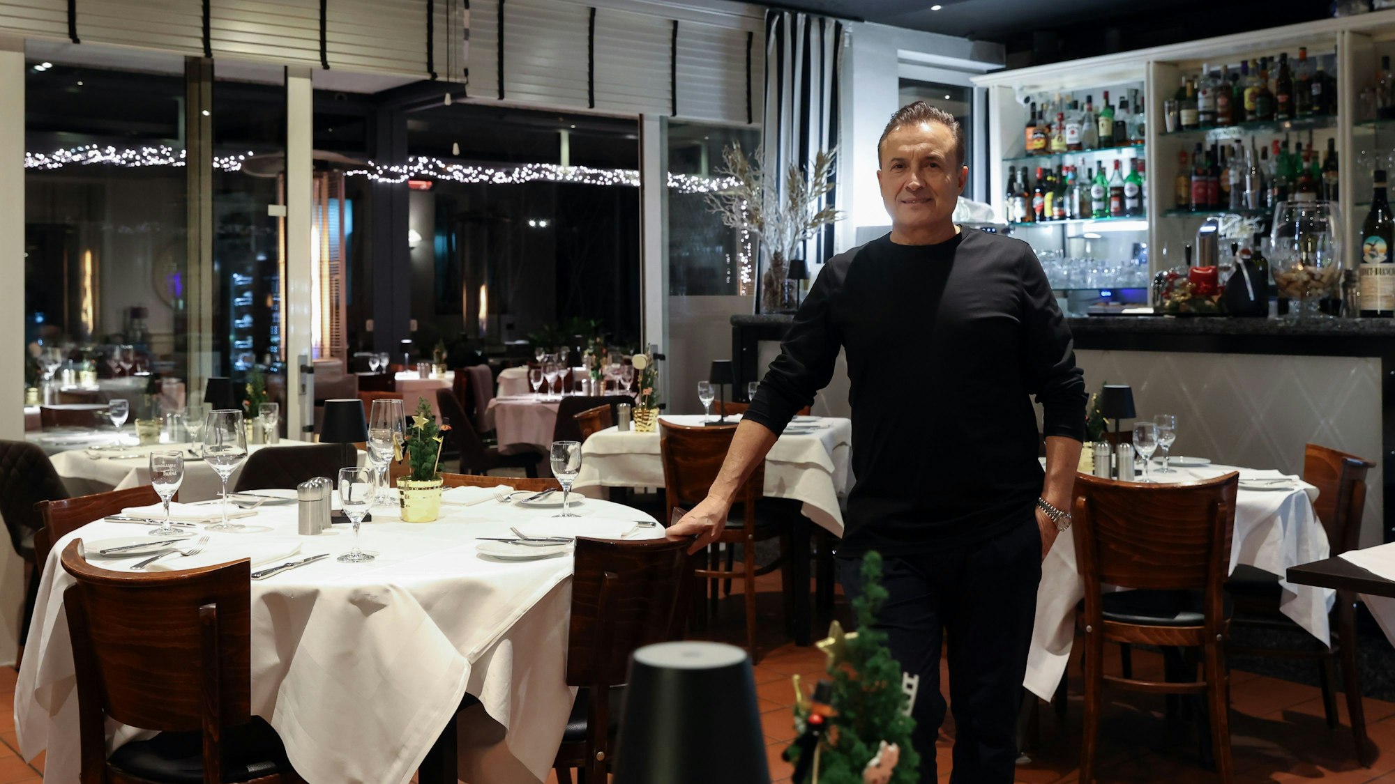 Ein Mann steht inmitten eines Raumes mit einer Vielzahl von Tischen.