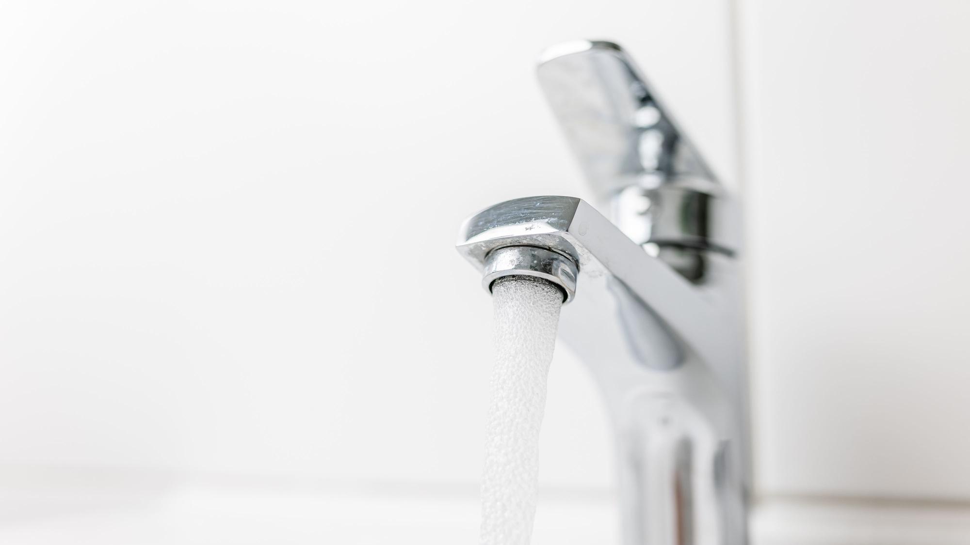 Zu sehen ist ein Wasserhahn, aus dem Wasser fließt.