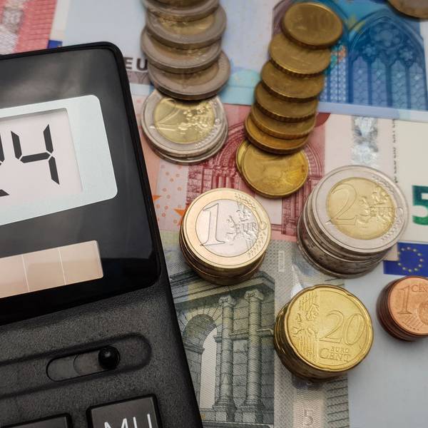 Ein Taschenrechner, auf dem 2024 steht, liegt auf verschiedenen Geldscheinen und -münzen