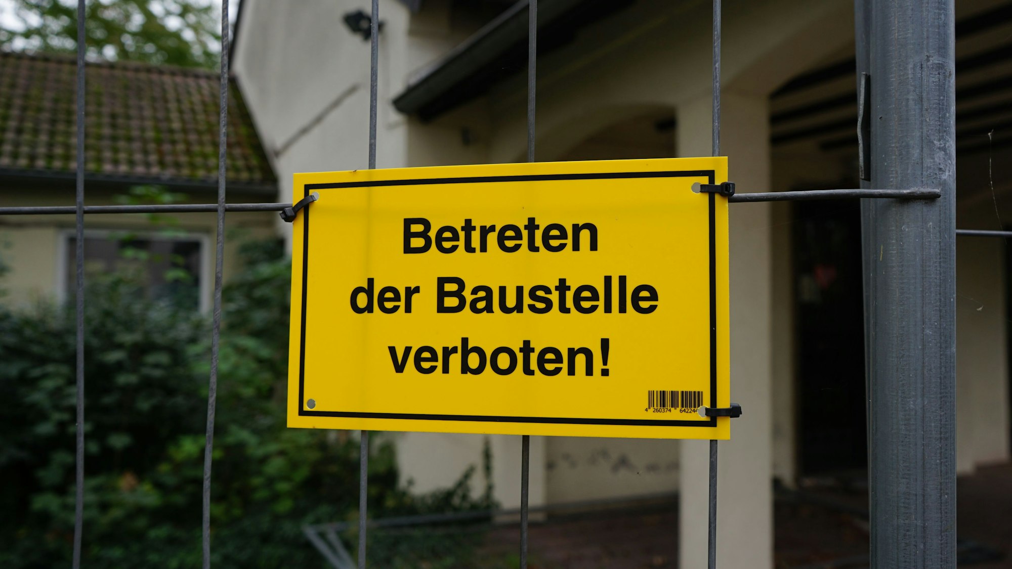 Ein gelbes Schild mit der Aufschrift „Betreten der Baustelle verboten!“ am Feuerwehrgerätehaus in Sindorf.