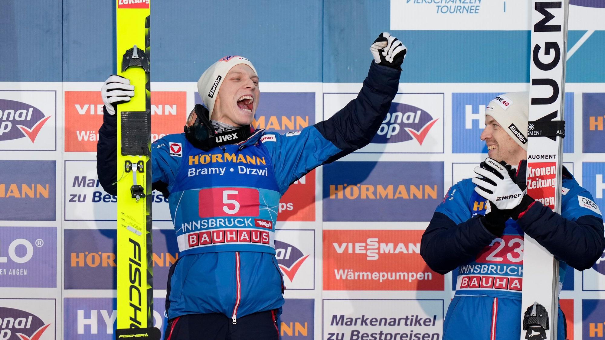 Jan Hoerl, of Austria, celebrates on the podium after winning the third stage of the 72th Four Hills ski jumping tournament in Innsbruck, Austria, Wednesday, Jan. 3, 2024. At right is this placed Michael Hayboeck, also of Austria. (AP Photo/Matthias Schrader)