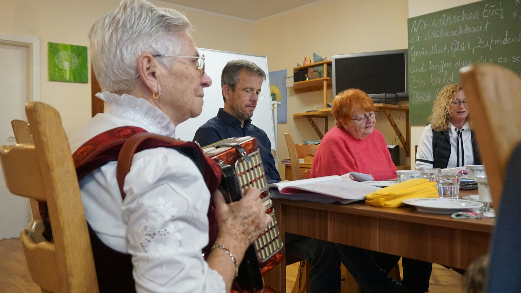 Eine ältere Frau trägt Tracht und spielt auf dem Akkordeon.
