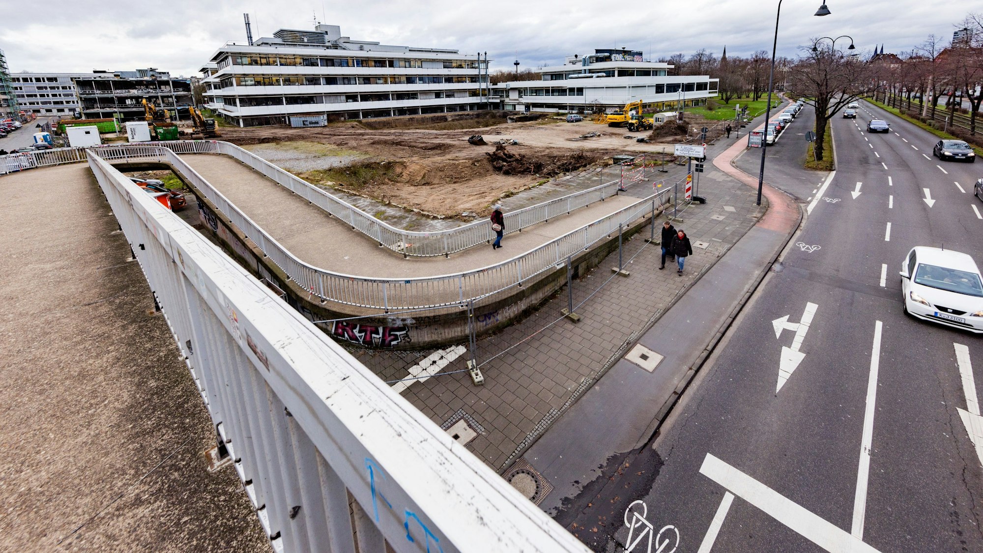 Fußgängerbrücke an einer vielspurigen Straße mit Baustelle im Hintergrund.