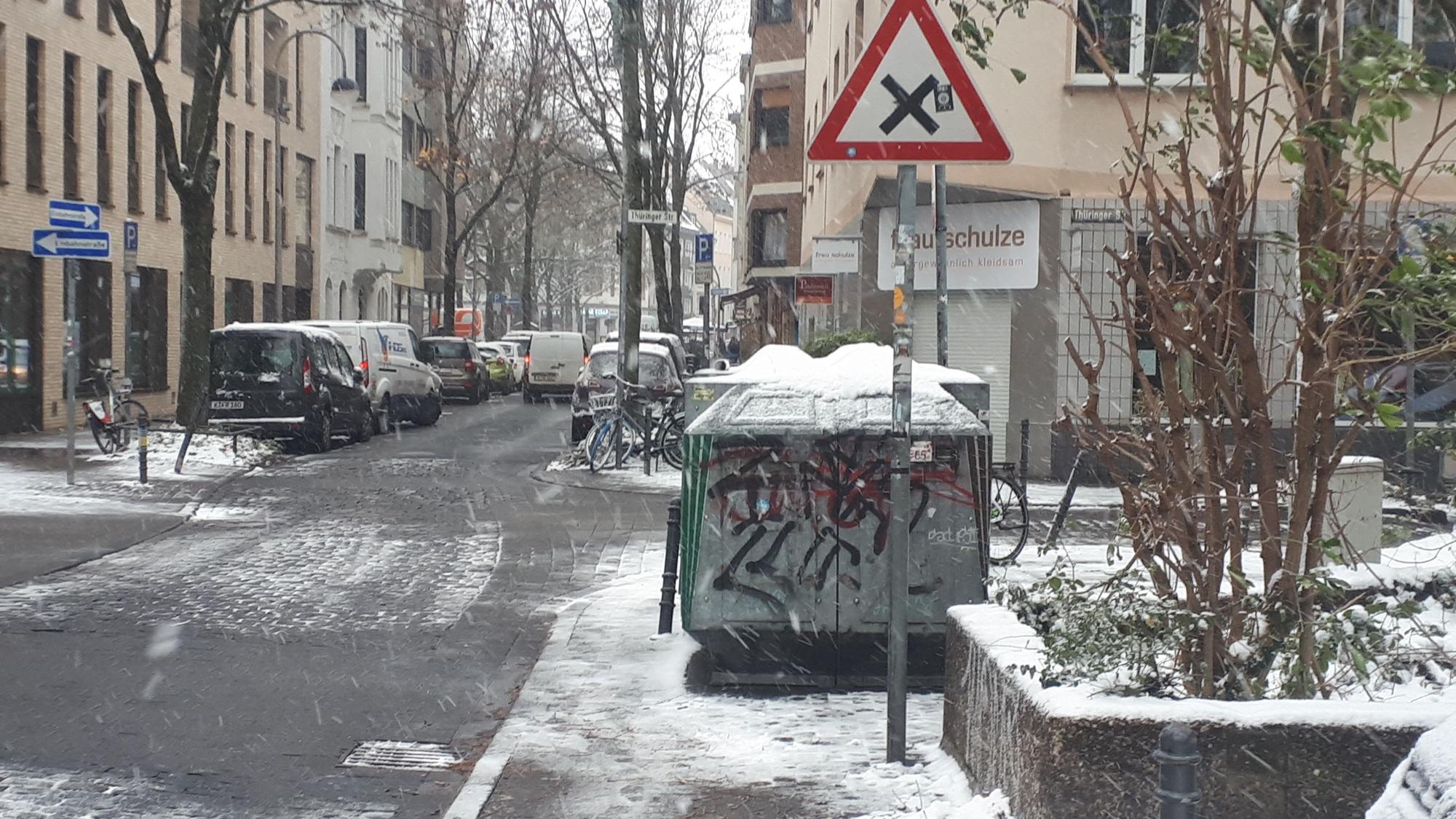 Ein Glascontainer steht auf dem Bürgersteig.