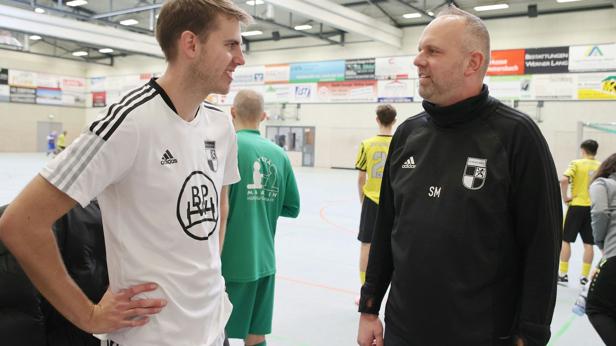 Blick auf zwei Fußballtrainer, die miteinander sprechen.
