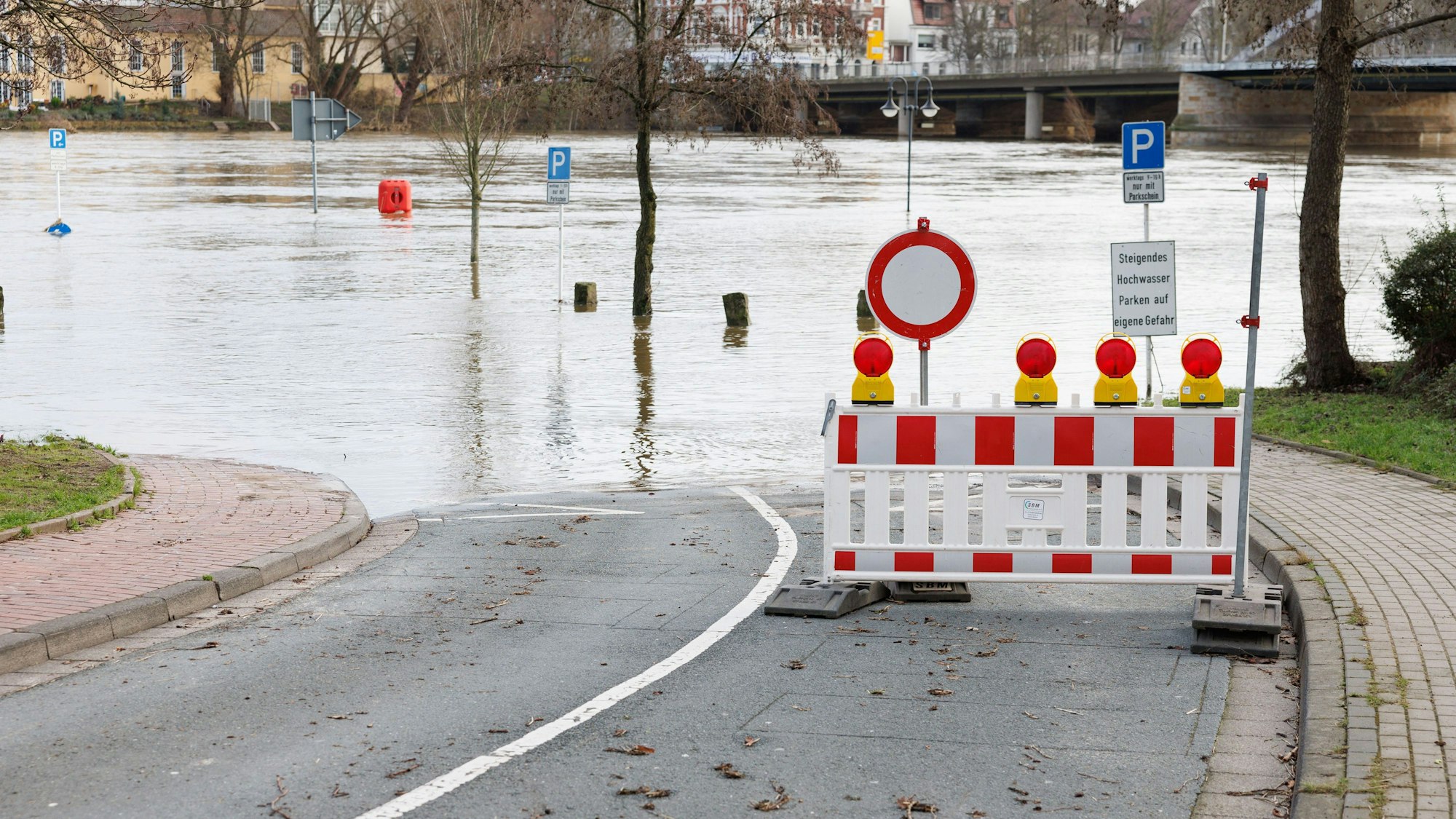 ARCHIV - 30.12.2023, Nordrhein-Westfalen, Minden: Blick auf die überflutete Zufahrt zum Parkplatz «Schlagde», einem alten Umschlageplatz und Uferhafen der Weser. (zu dpa: «Dauerregen lässt Hochwassergefahr wieder steigen») Foto: Friso Gentsch/dpa +++ dpa-Bildfunk +++