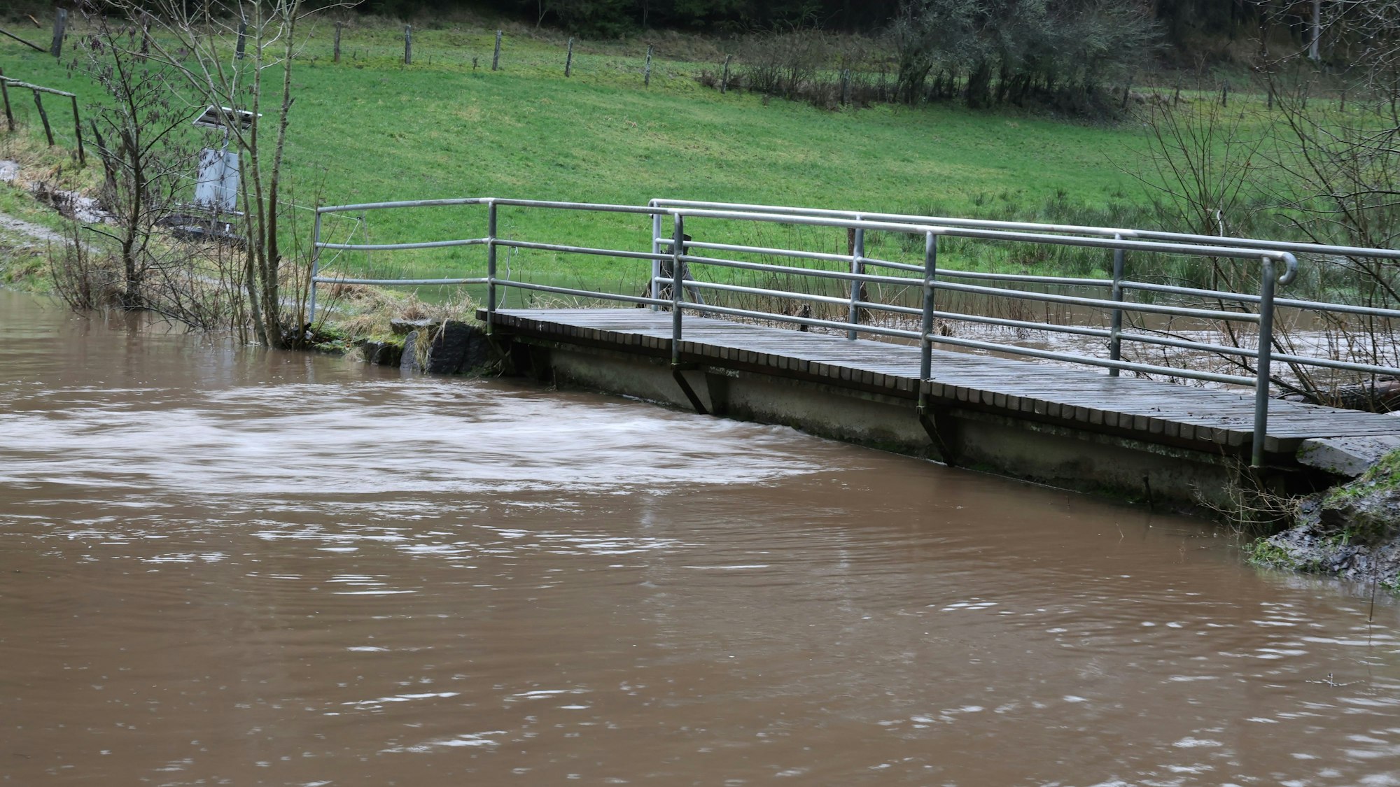 Der Wolferter Bach ist über die Ufer getreten, das Wasser steht bis n führt Hochwasser.