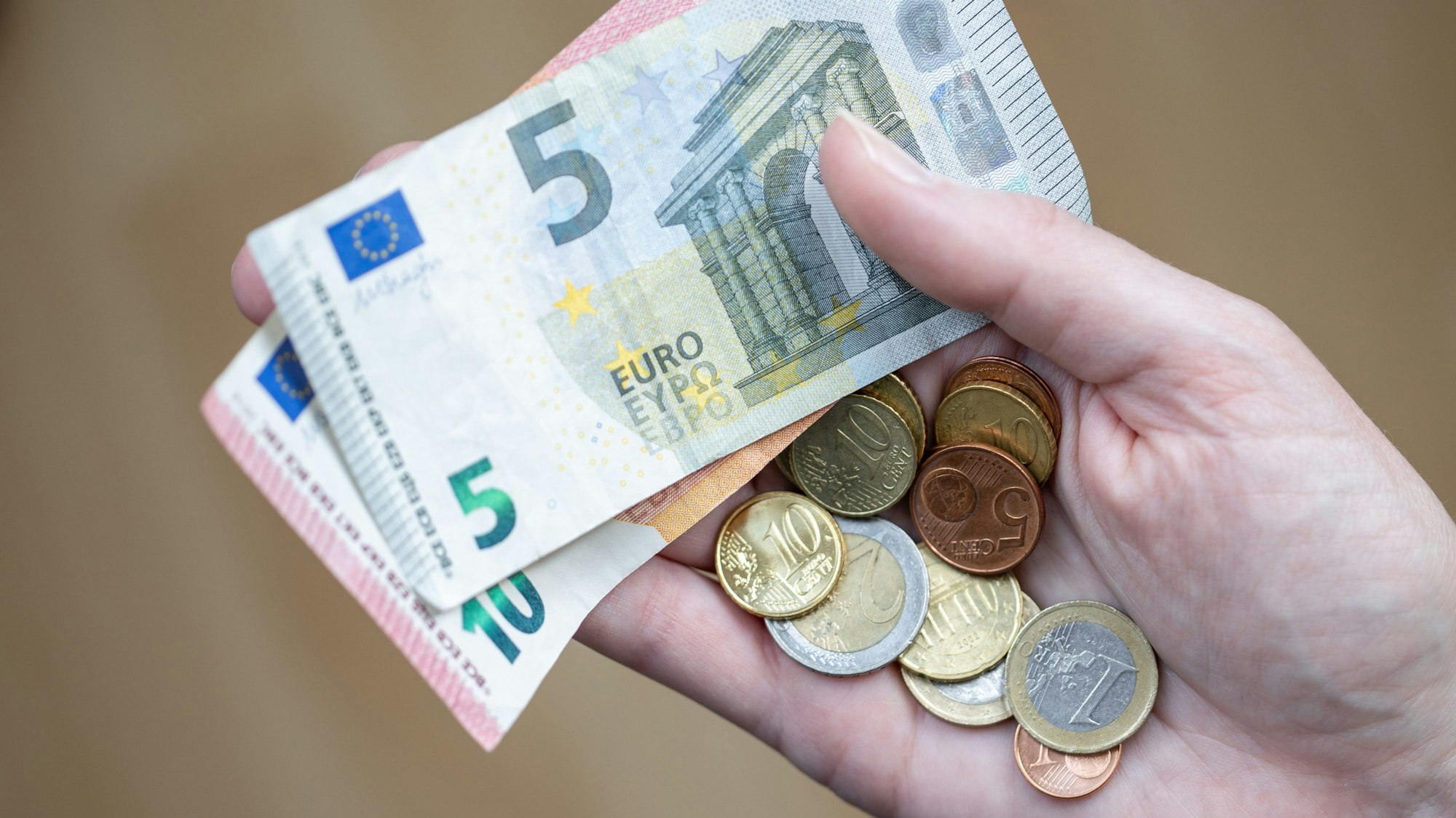 ARCHIV - 09.04.2021, Bayern, Nürnberg: Eine Frau hält Geldscheine und Münzen in der Hand. Der Kampf gegen steigende Verbraucherpreise gehört einer Umfrage zufolge für viele zu den wichtigsten Aufgaben der Politik im neuen Jahr. (Zu dpa "Umfrage: Kampf gegen Inflation für viele Menschen wichtiges Thema") Foto: Daniel Karmann/dpa +++ dpa-Bildfunk +++