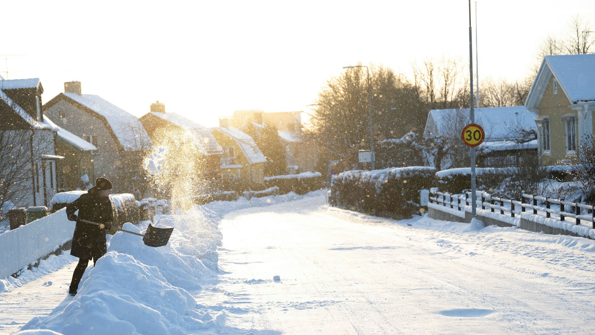 A woman shovels her sidewalk in the snowy and cold January weather.
