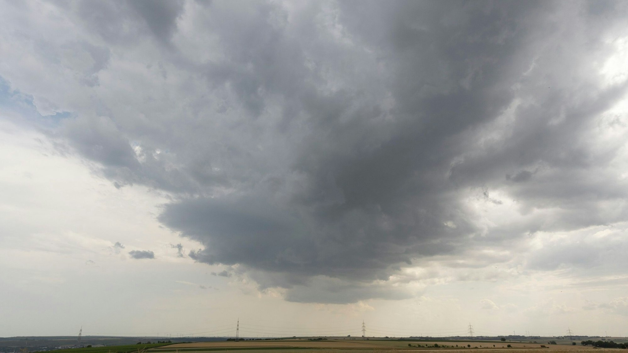 Ein anziehendes Gewitter bildet sich am Himmel über Deutschland. Im Hintergrund sind dunkle Wolken zu sehen. (Symbolbild)