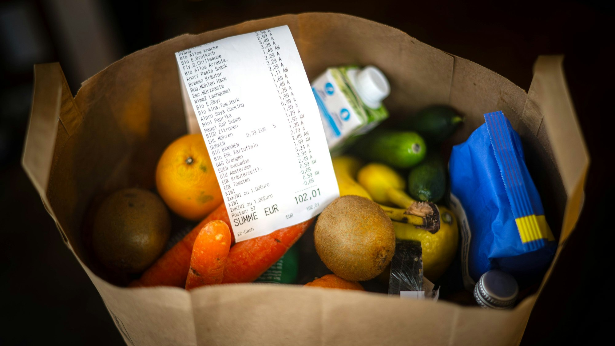 Ein Kassenbon liegt auf den Lebensmitteln in einer Einkaufstüte.