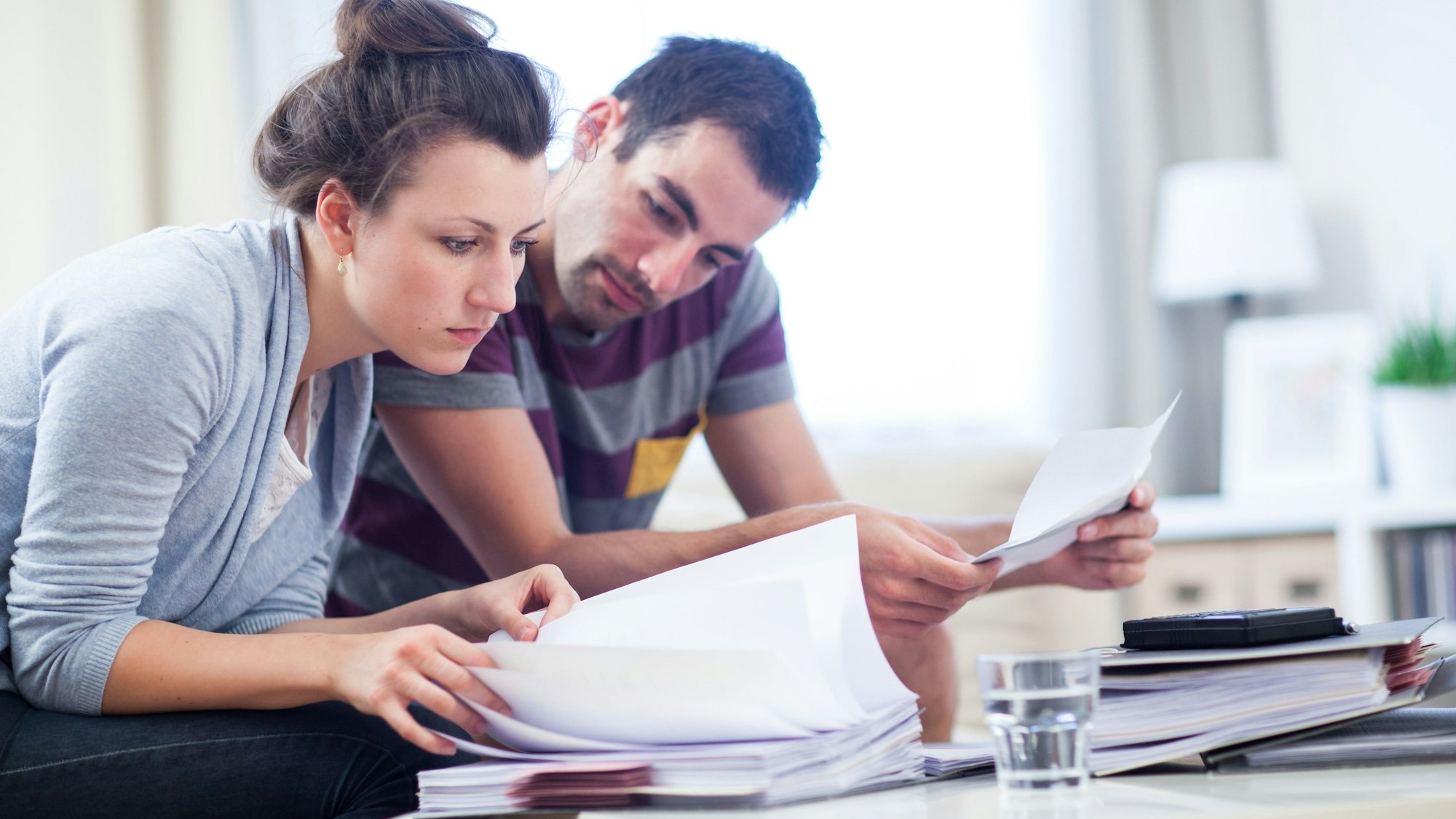 Eine Frau und ein Mann beugen sich über Aktenordner