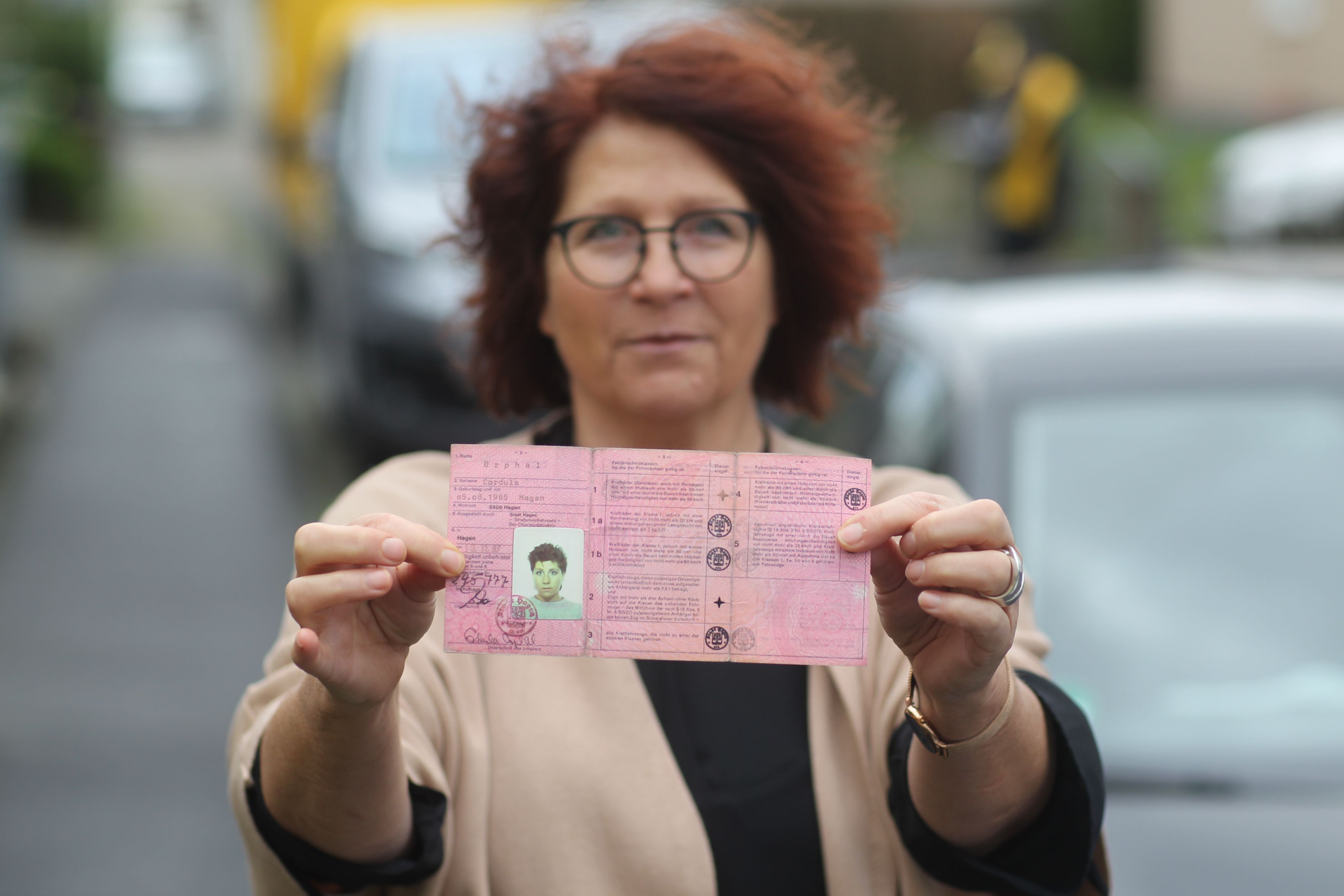 Eine Frau hält ihren alten Führerschein in die Kamera.