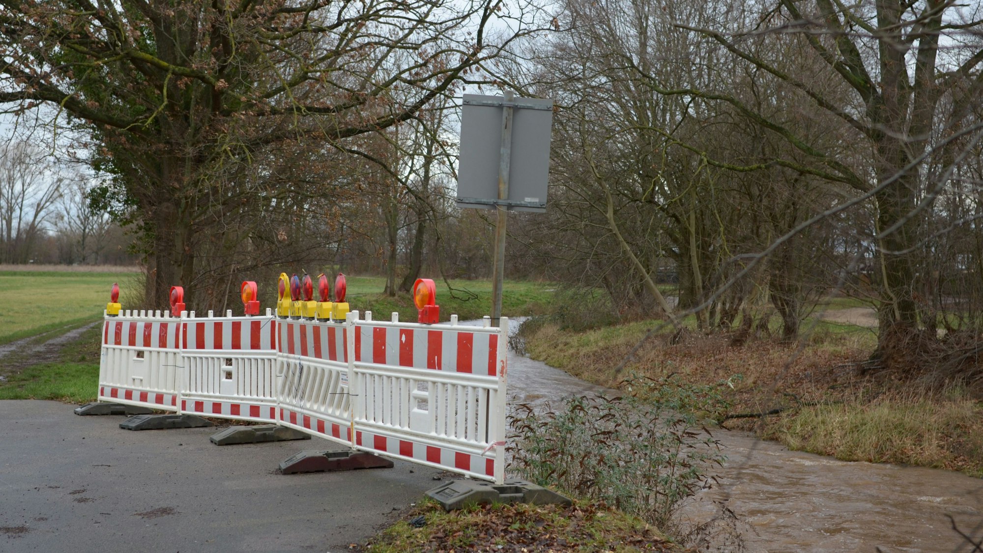 Ein rot-weißer Sperrzaun steht am Erftufer an der Stelle, wo früher eine Brücke über den Fluss führte.