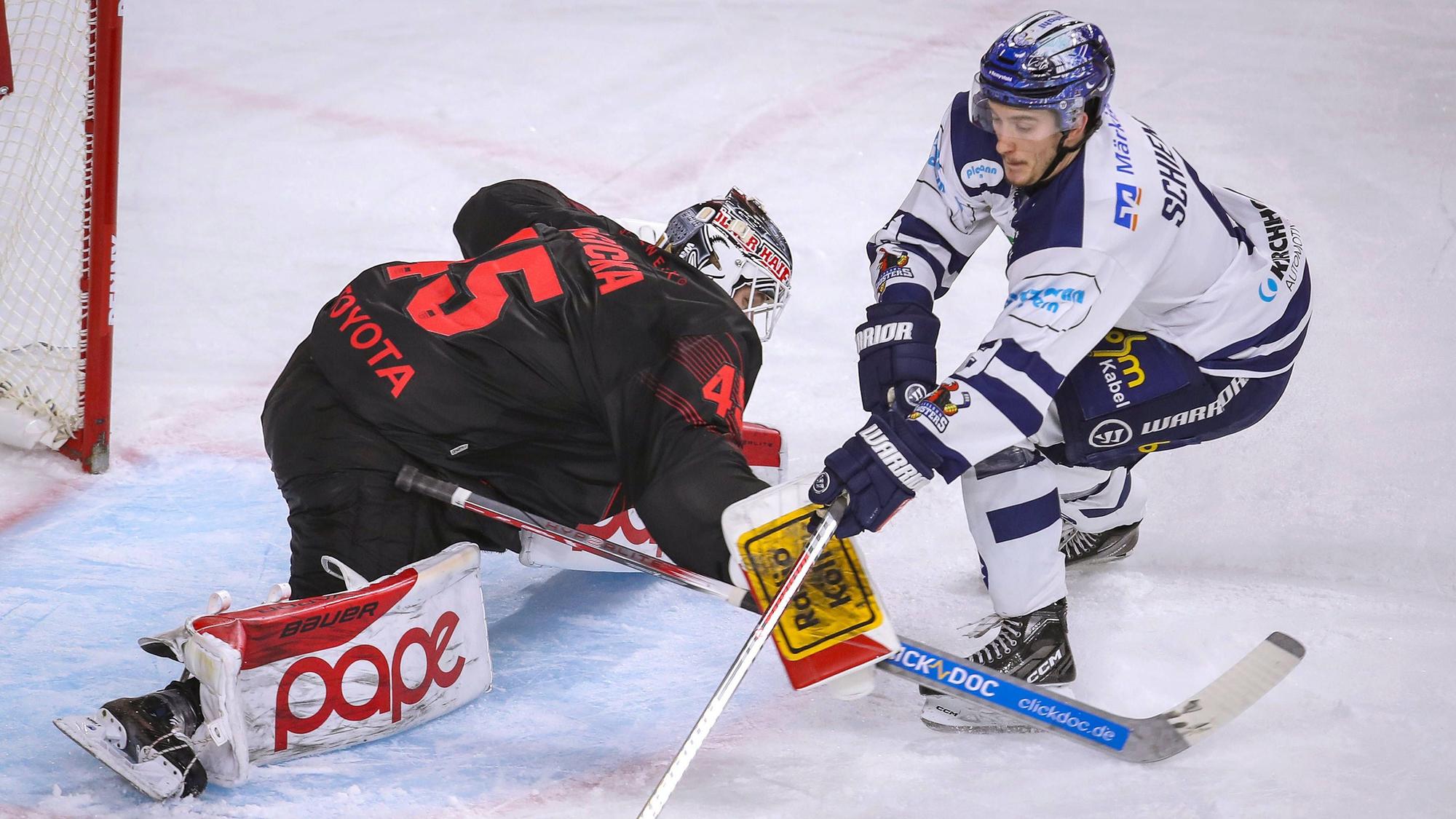 Zwei Eishockeyspieler versuchen den Puck unter Kontrolle zu bekommen.