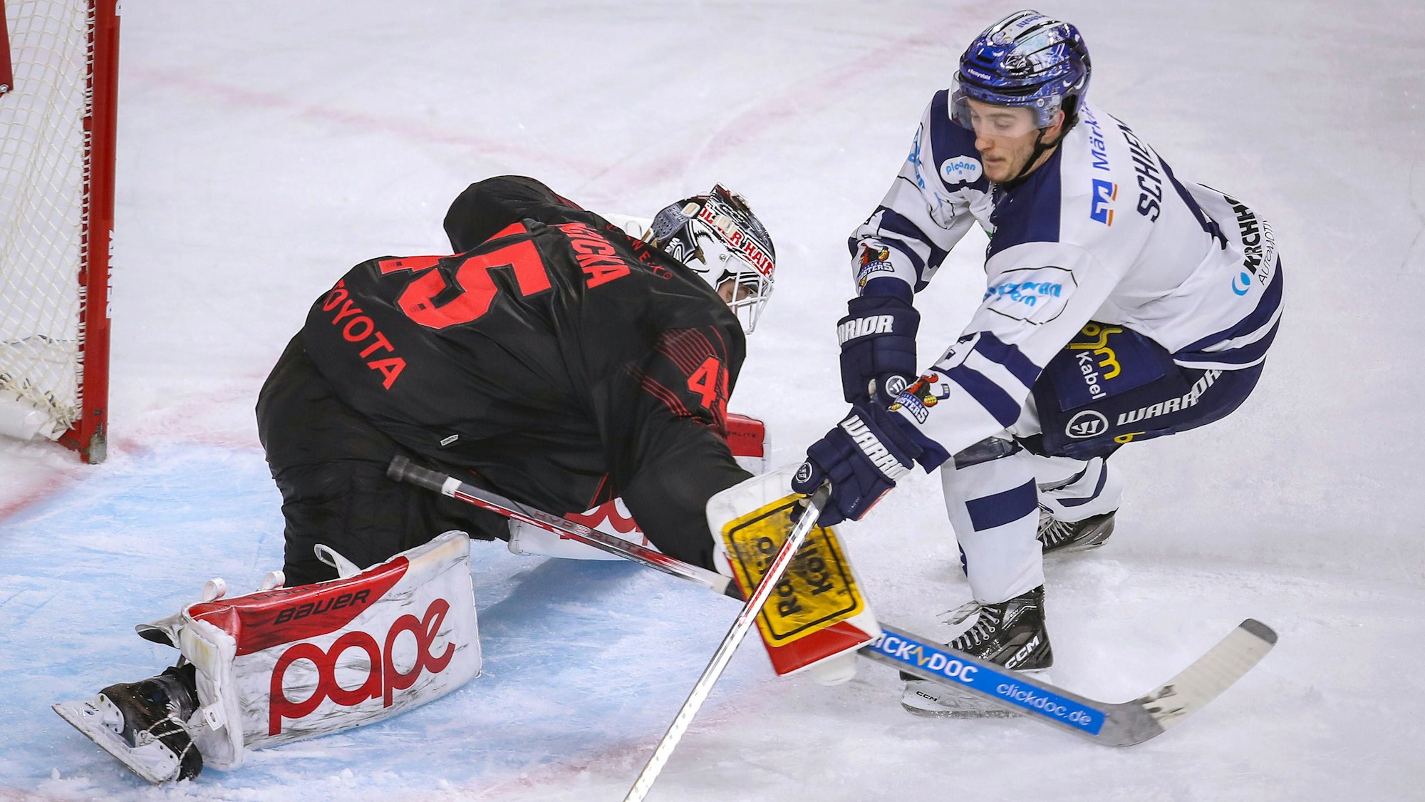Zwei Eishockeyspieler versuchen den Puck unter Kontrolle zu bekommen.