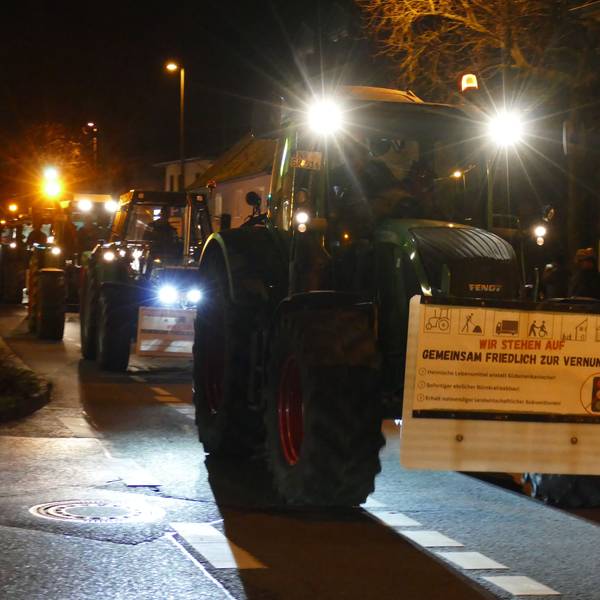 Ein Protestzug aus Traktoren fährt über eine Straße.