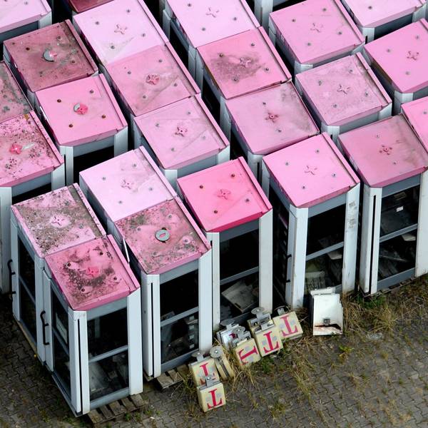Die Luftbildaufnahme zeigt ausrangierte Telefonzellen der Telekom mit magenatfarbenen Dächern.