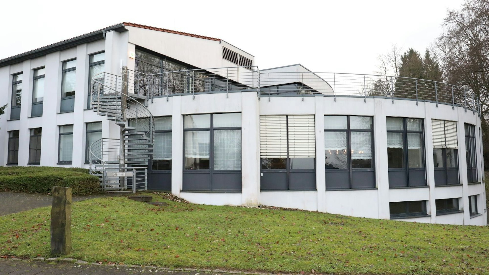Ein weißes Gebäude, zum Teil in Bogenform gebaut, mit großen Fensterflächen