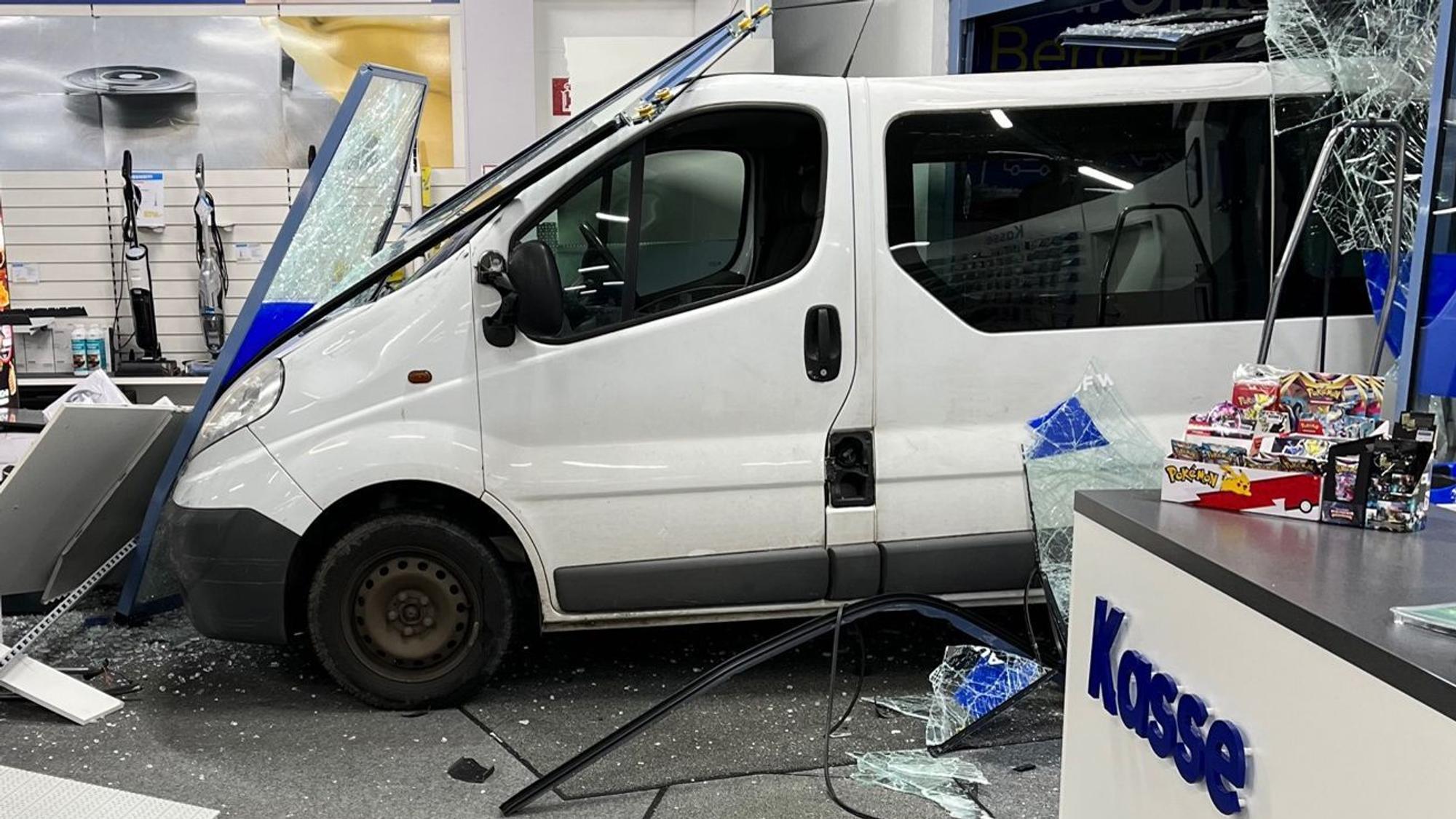 Ein weißer Lieferwagen steht in einem Geschäft. Die Scheibe der Eingangstüre ist zerbrochen. Überall liegen Scherben.