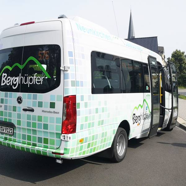Ein Kleinbus mit der Aufschrift „Berghüpfer“ in den Farben grün und weiß.