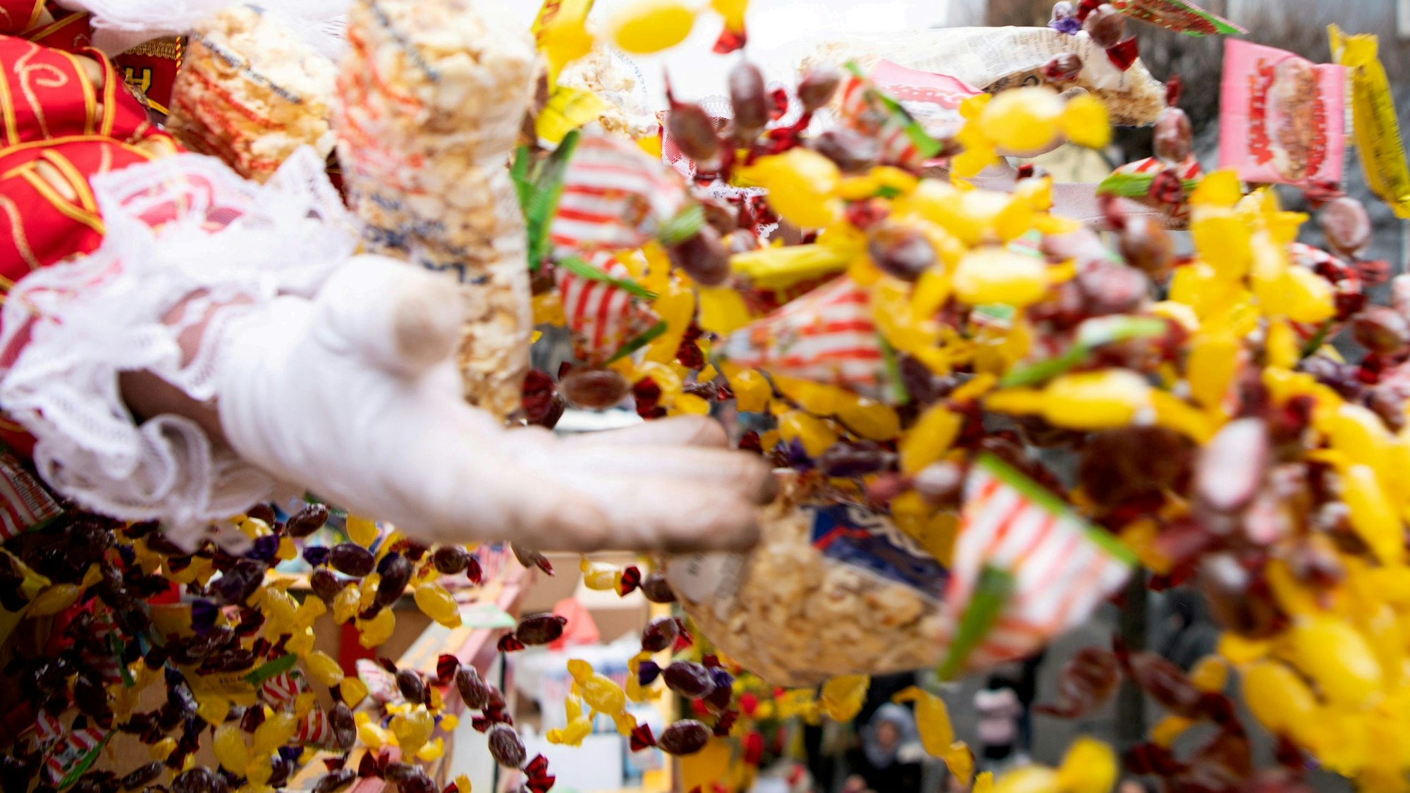 Das Bild zeigt eine Tollität, wie sie mit beiden Händen eine große Anzahl an Kamelle wirft.