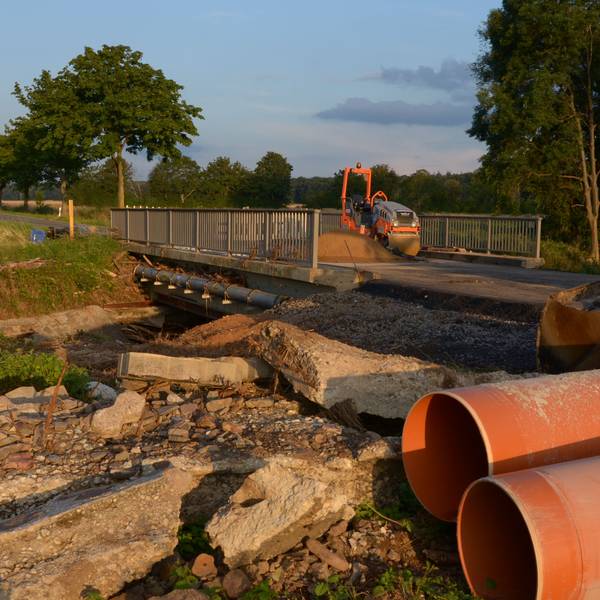 Neben der Orbachbrücke bei Palmersheim, die durch das Hochwasser schwer beschädigt wurde, liegen Betontrümmer. Auf der Fahrbahn stehen zwei Bagger für Reparaturarbeiten.