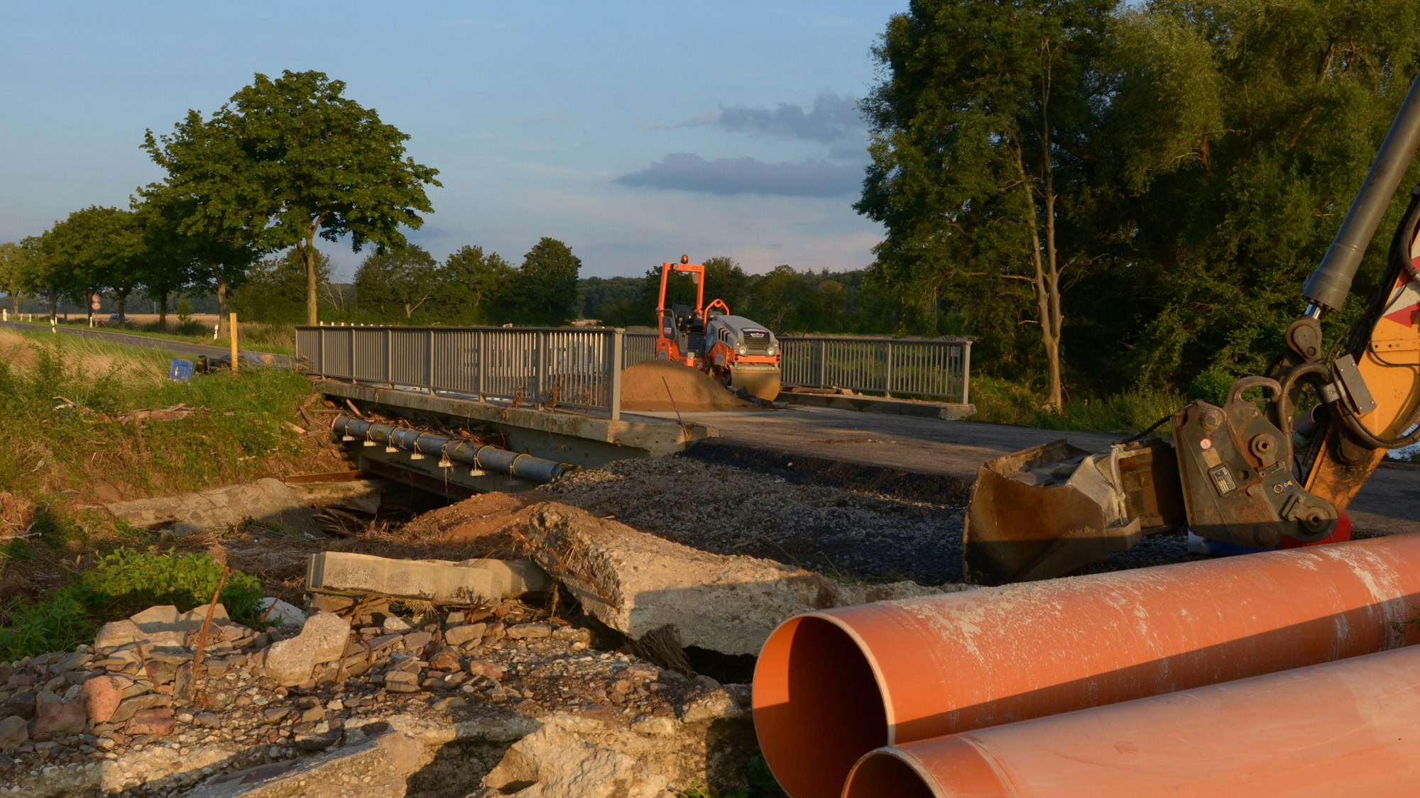 Neben der Orbachbrücke bei Palmersheim, die durch das Hochwasser schwer beschädigt wurde, liegen Betontrümmer. Auf der Fahrbahn stehen zwei Bagger für Reparaturarbeiten.