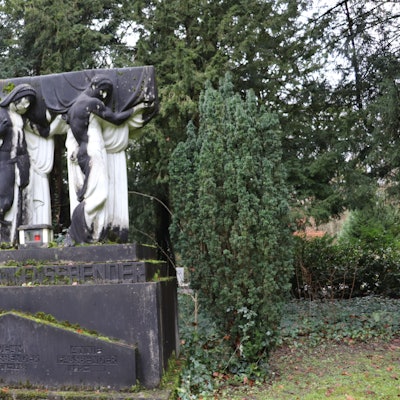 Vier weiße lebensgroße Marmorfiguren, stehn auf einem Sockel und tragen einen Sarg