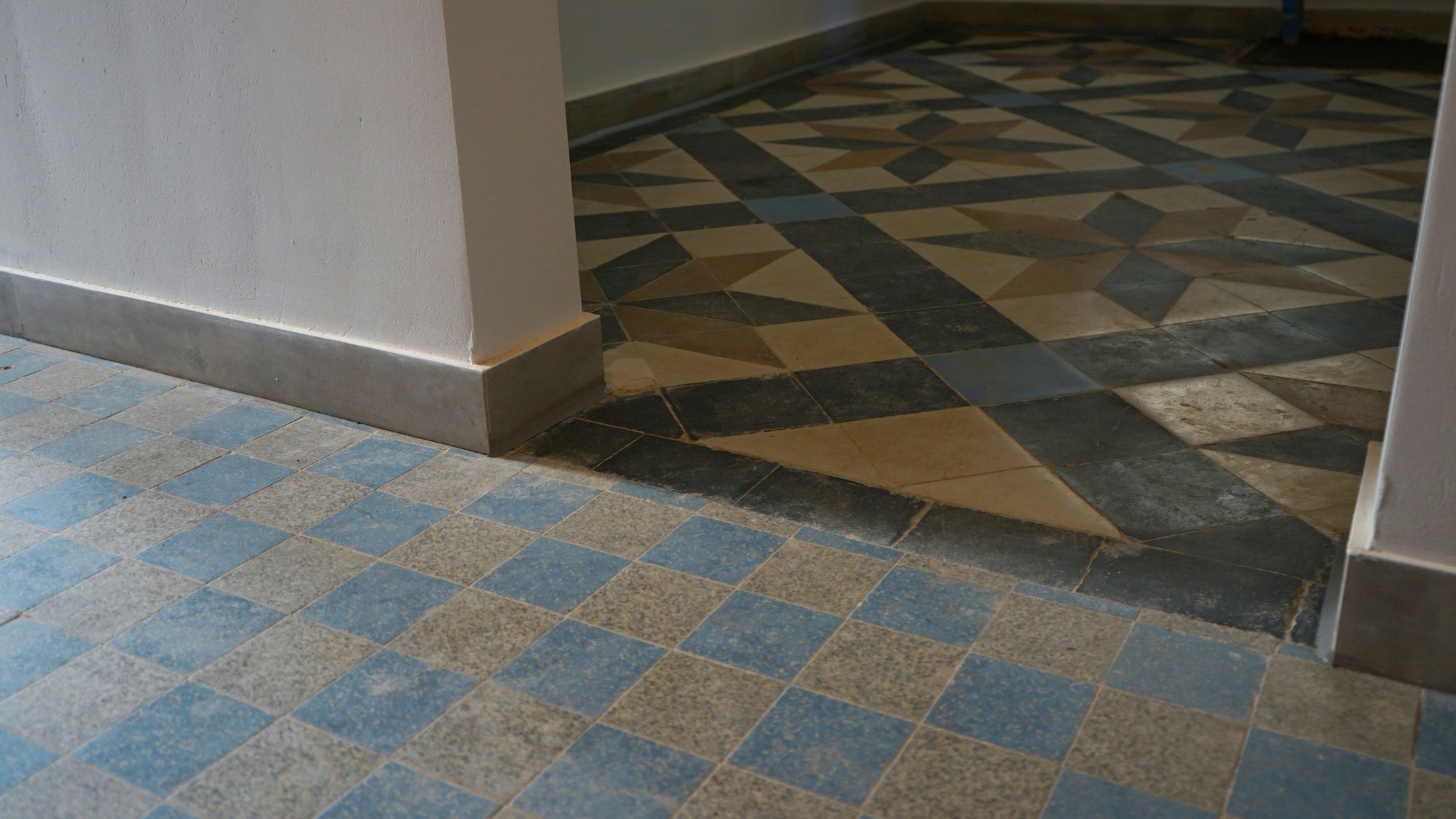 Zu sehen ist ein Fliesenboden mit historischen Fliesen, die kariert und in Form von Sternen verlegt wurden.
