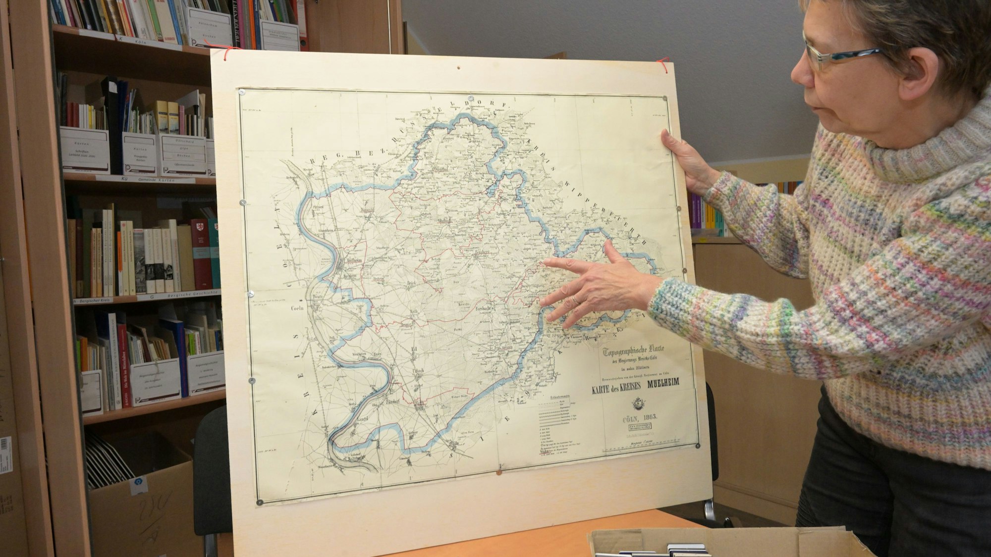 Elisabeth Coester zeigt eine historische Karte des Landkreises Mülheim am Rhein.