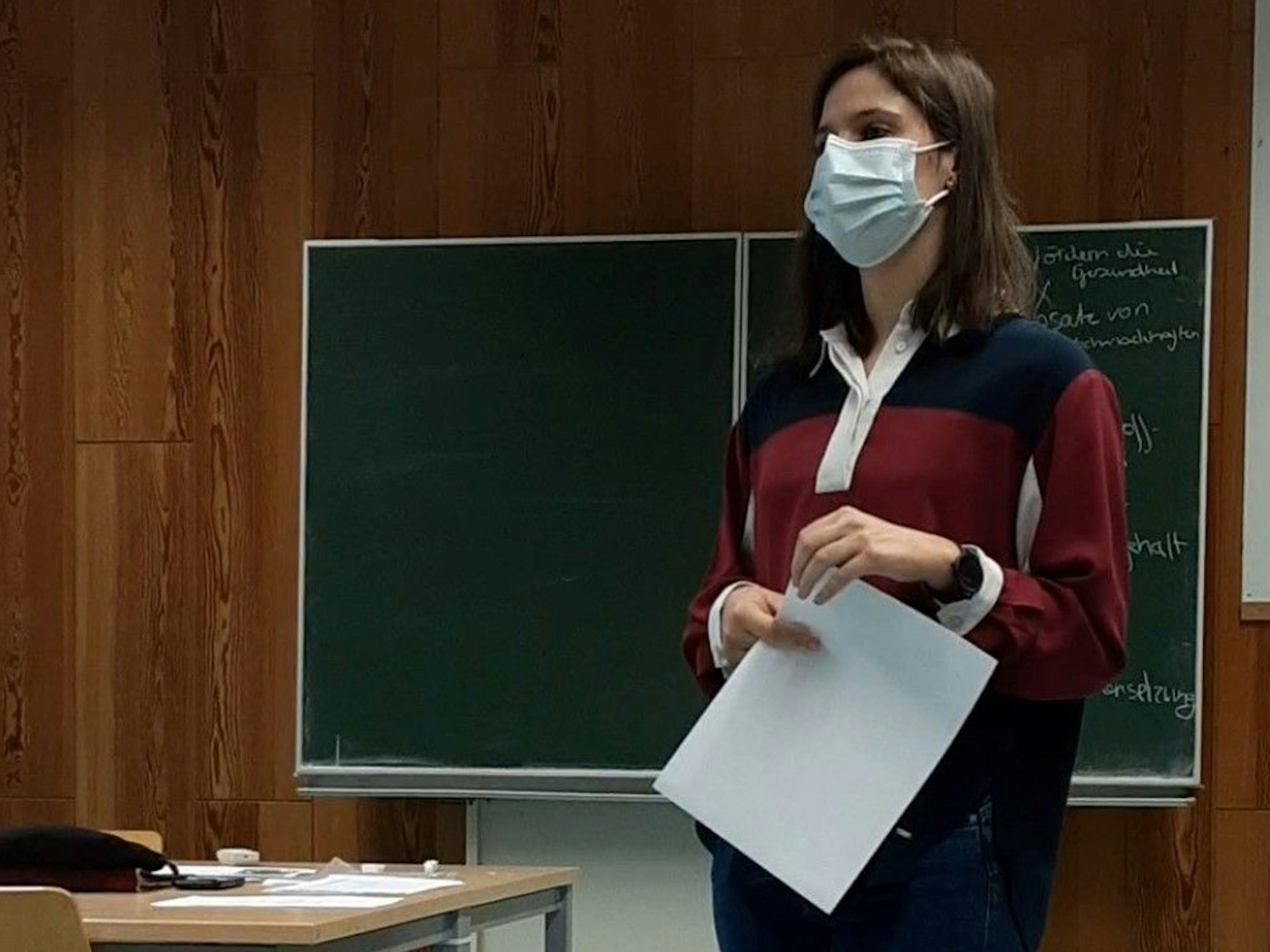 Kathrin Dahmen steht mit Maske vor einer Schultafel.