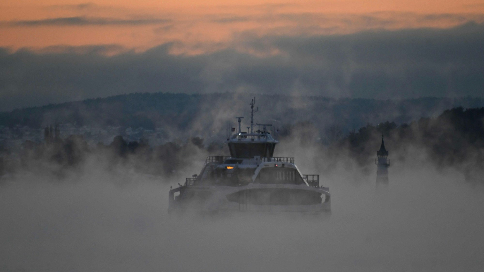 A ferry sails through the Oslo fjord on the evening of January 5, 2023, as the city endures unusual cold, reaching minus 22°C. (Photo by Olivier MORIN / AFP)