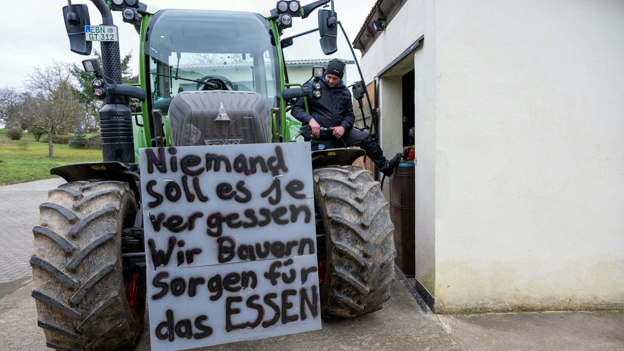 Ein Landwirt betankt seinen Schlepper mit Diesel in Vorbereitung auf die anstehende Protestwoche - am Traktor hängt bereits ein Schild mit der Aufschrift «Niemand soll es je vergessen. Wir Bauern sorgen für das Essen».