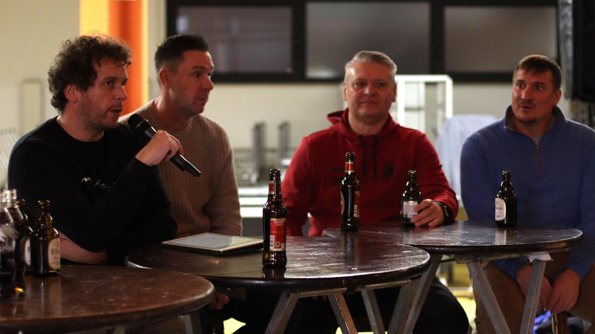 Moderator Tom Steinicke hält das Mikrofon in der Hand, neben ihm sitzen Uwe Metternich, Guido Mertens und Fabian Ewertz.