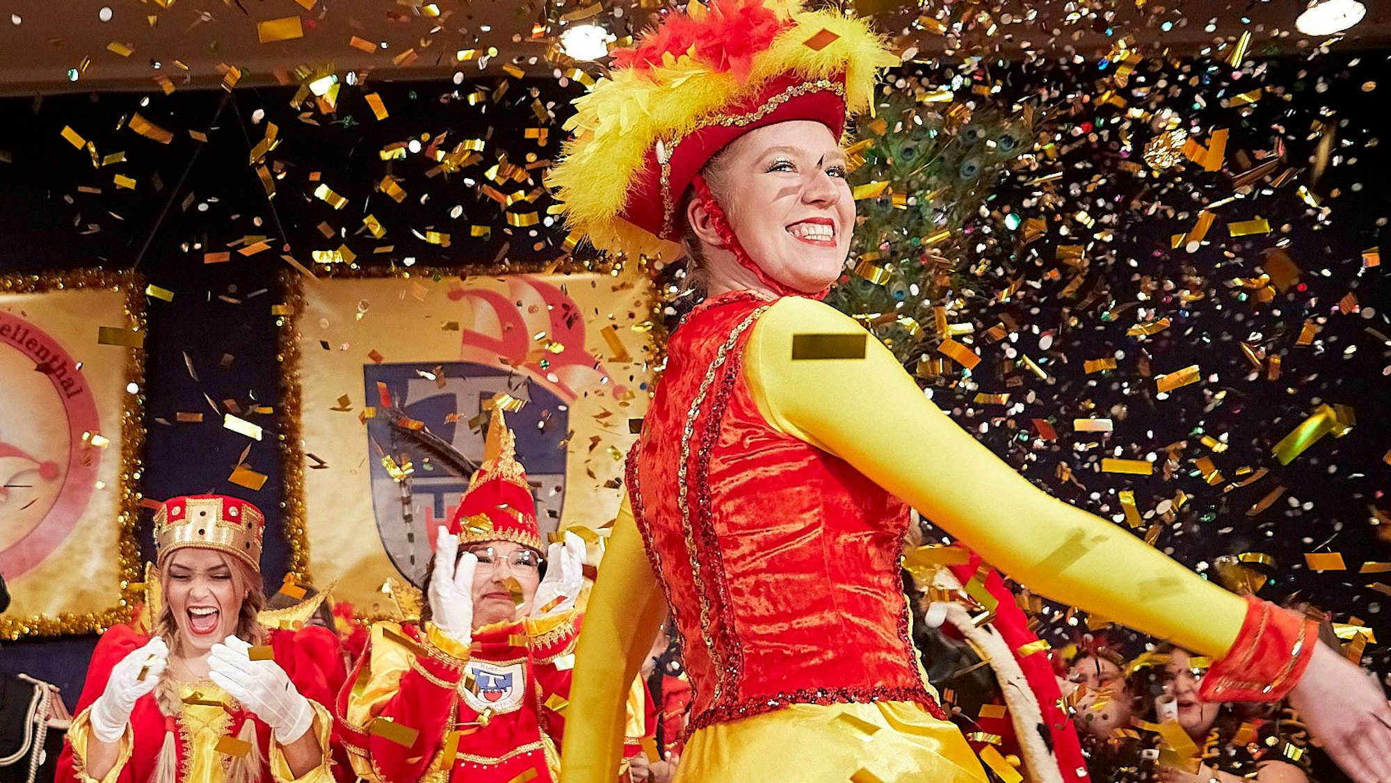 Eine in Rot und Gelb gewandete Tänzerin tanzt im Konfettiregen.