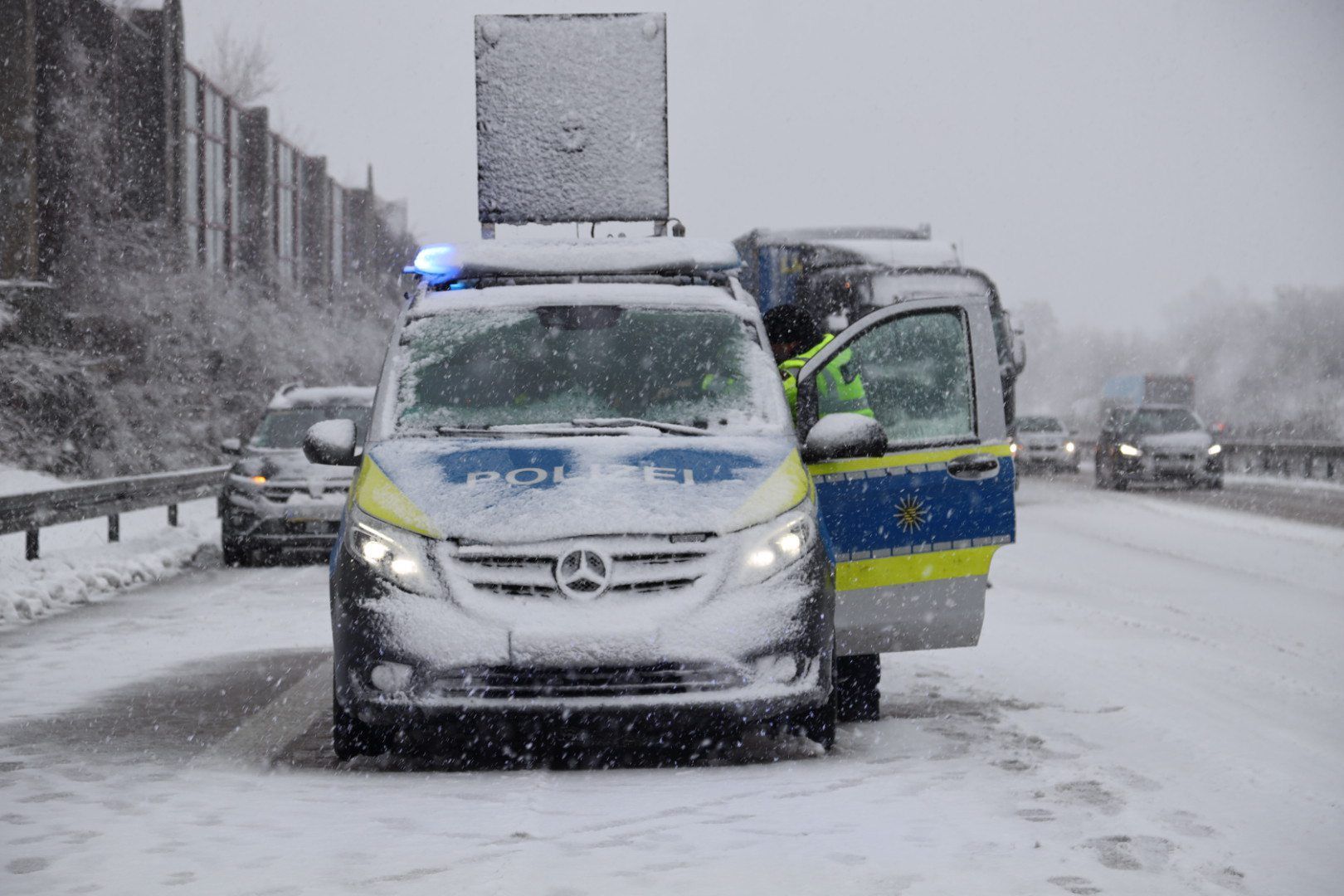 Polizeibeamte stehen auf einer Autobahn nach einem Unfall wegen Schnees und Glätte.