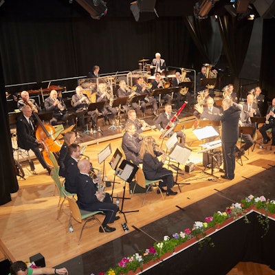 Das Landespolizeiorchester auf der Bühne im Gemünder Kursaal, die mit Blumen dekoriert ist.