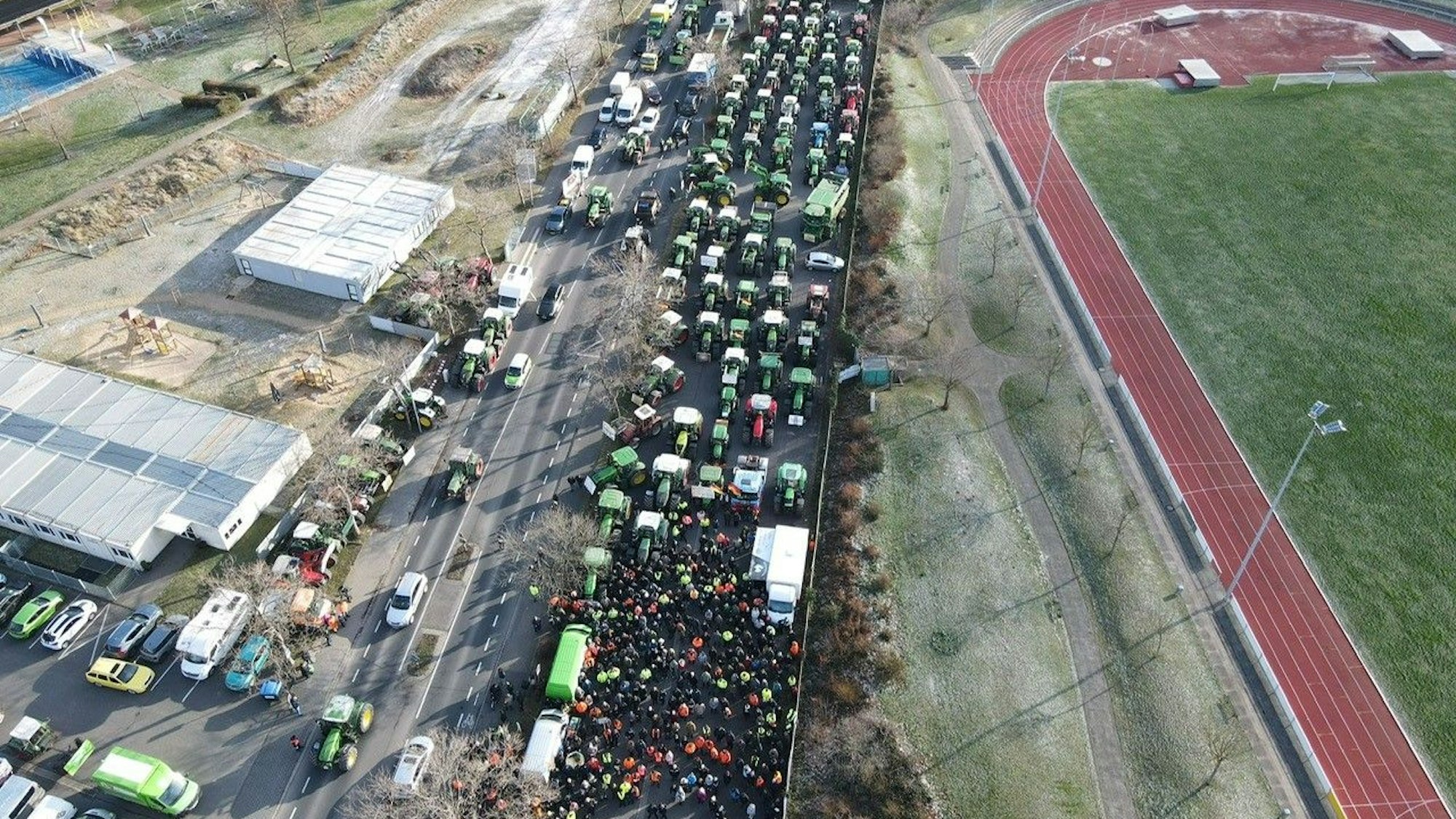 Zahlreiche Demonstranten stehen am Euskirchener Erftstadion. Hinter ihnen sind viele Traktoren geparkt.