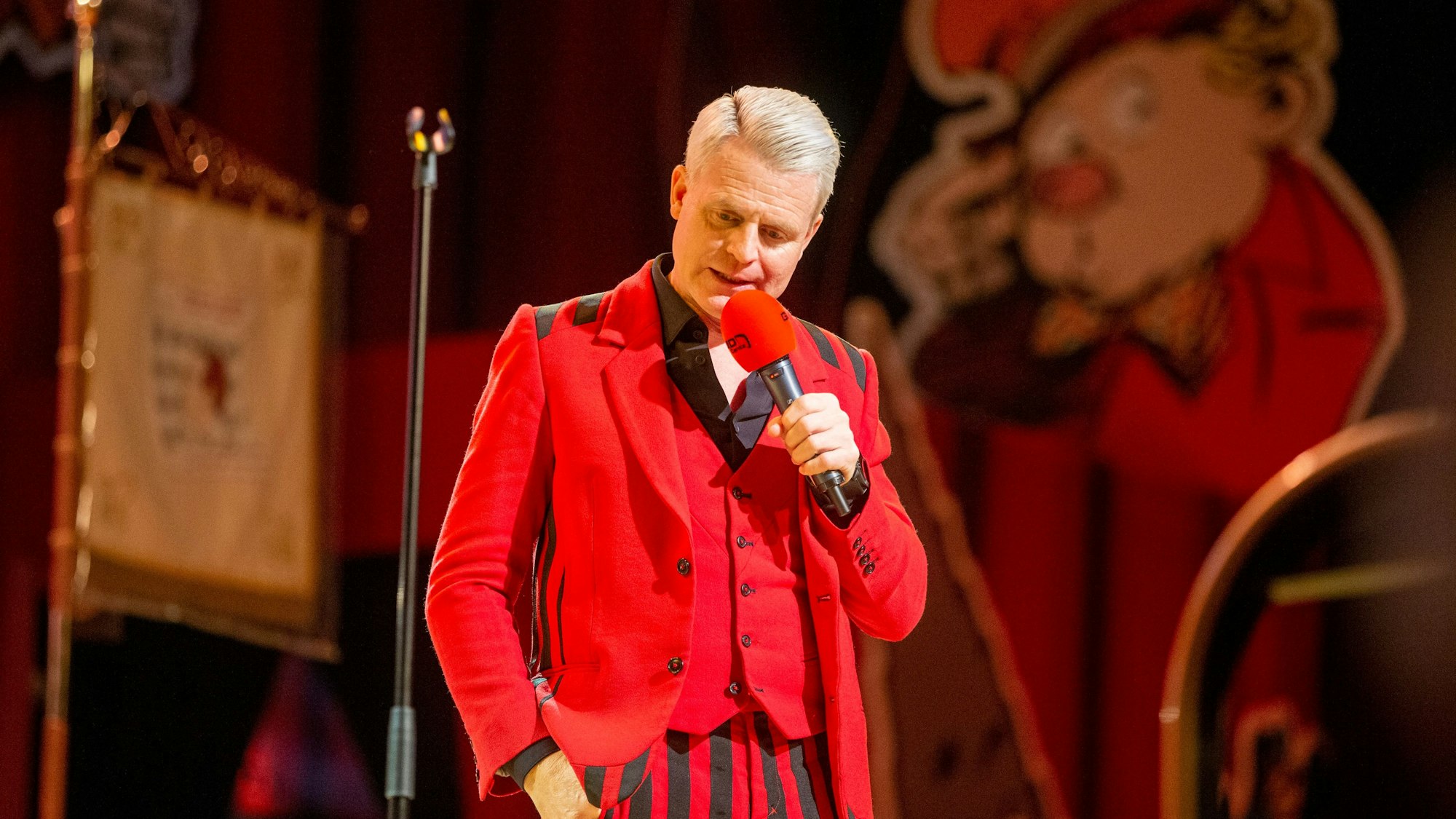 Guido Cantz im roten Maßanzug.