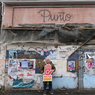 Ein Mann steht vor einem verrammelten Haus.