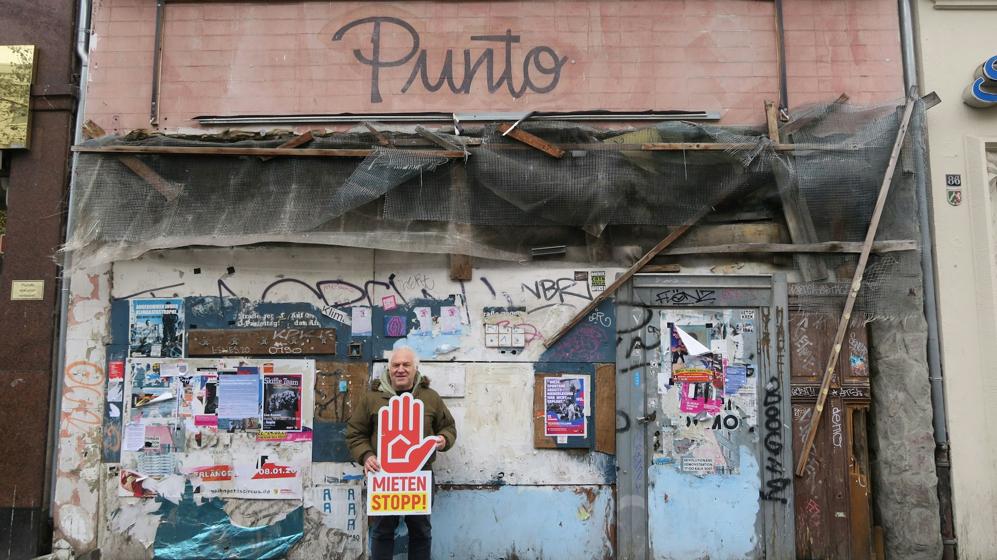 Ein Mann steht vor einem verrammelten Haus.