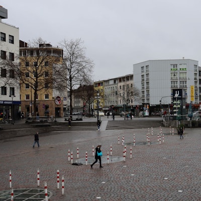 Wenige Fußgänger queren einen Platz mit einem zeltartigen Lokal.